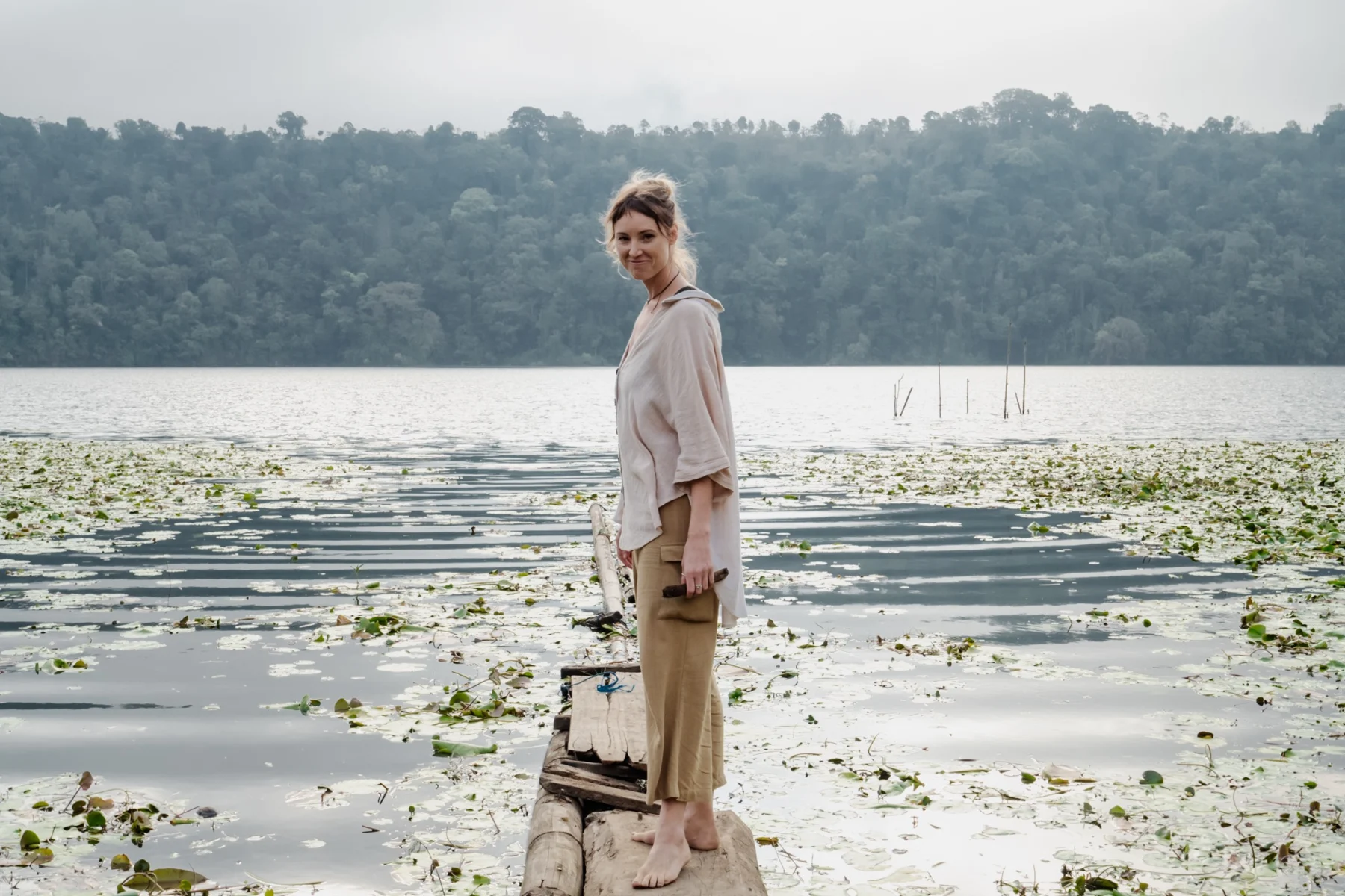 Max standing beside a peaceful lake dotted with water plants