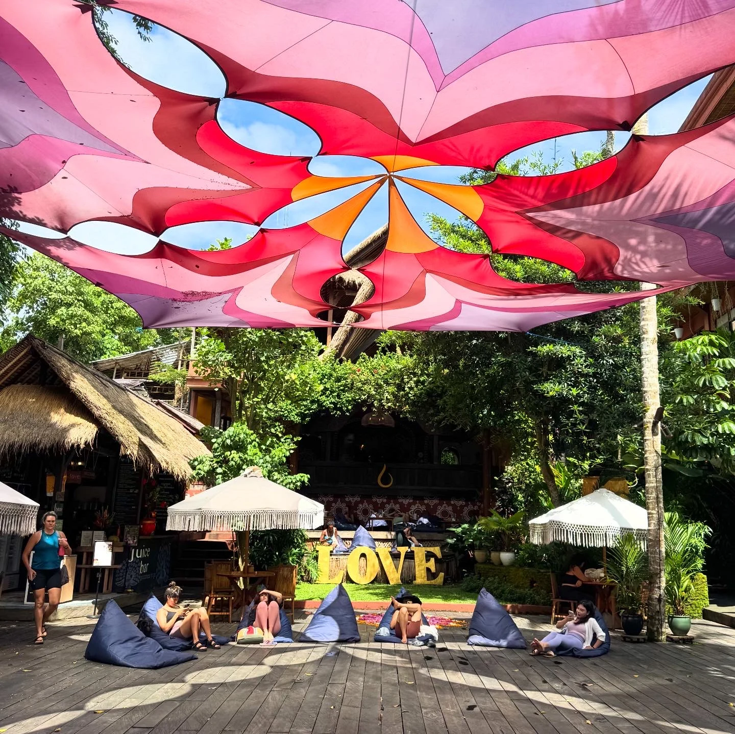 A colourful canopy above an outdoor gathering space with a LOVE sign