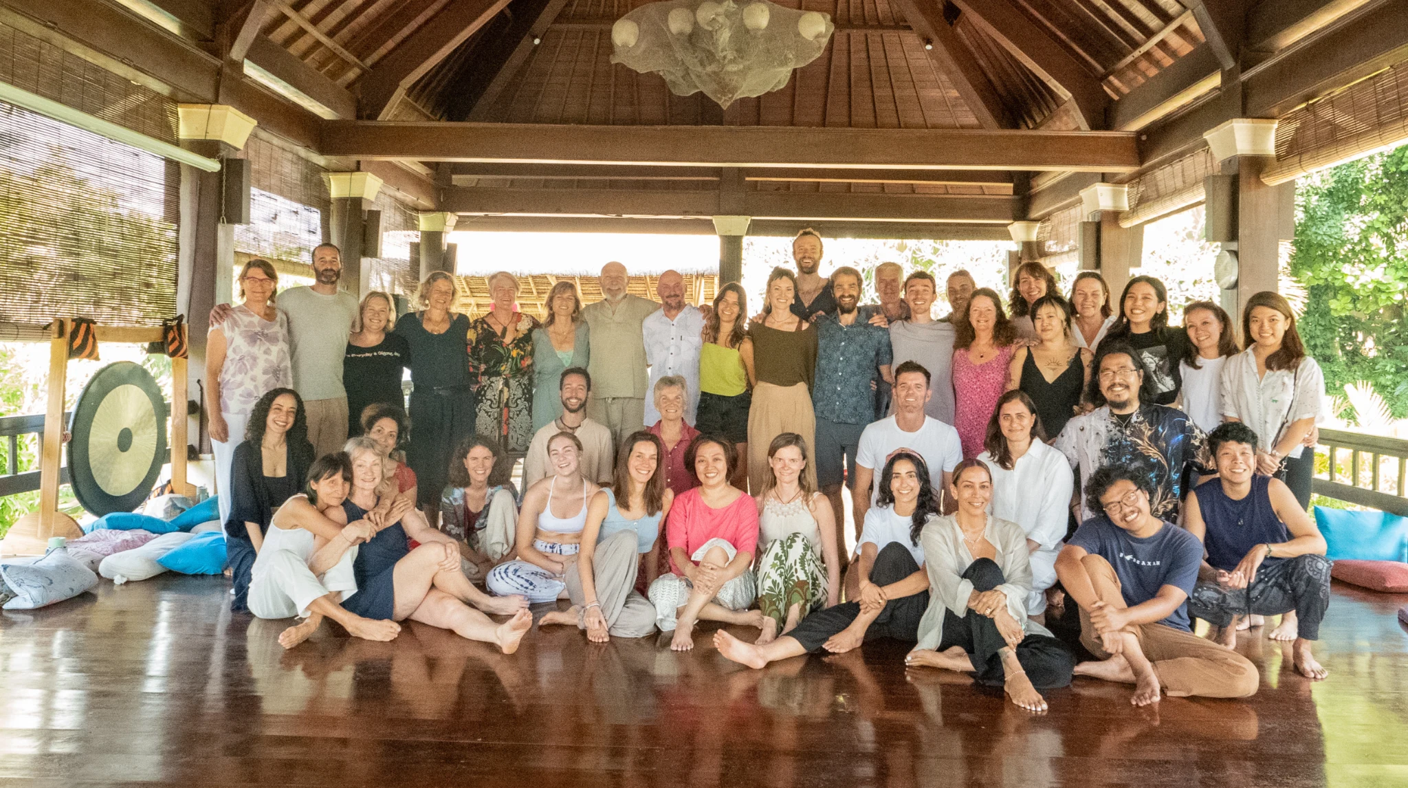 A group gathered together inside a wooden yoga pavilion