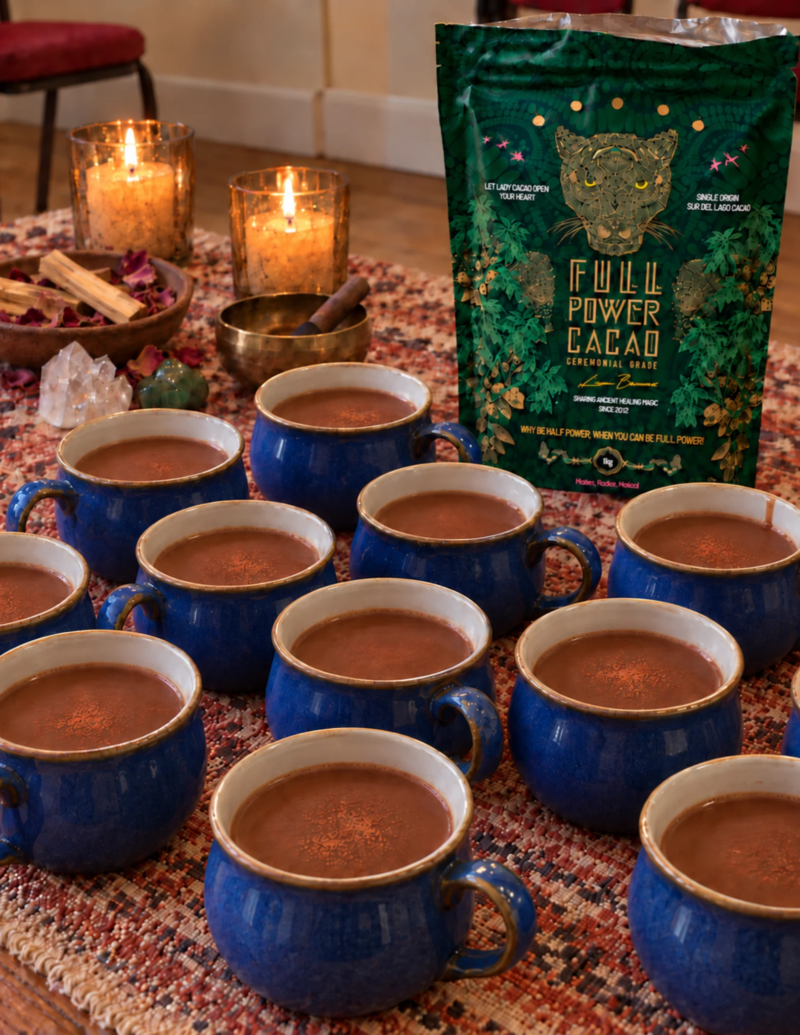 Blue cups of cacao arranged beside candles for a ceremony