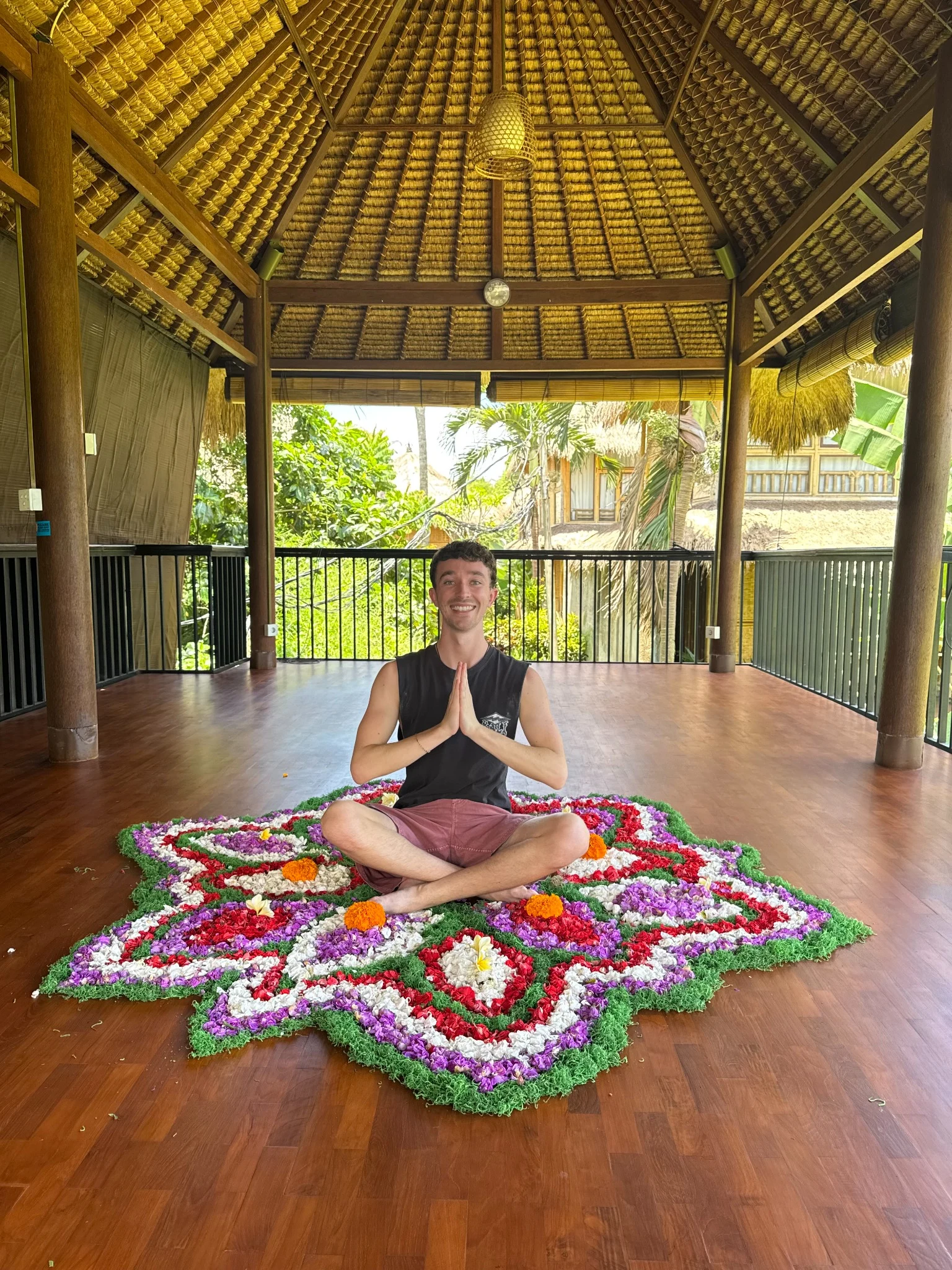 Max seated behind a colourful flower mandala in a wooden yoga pavilion