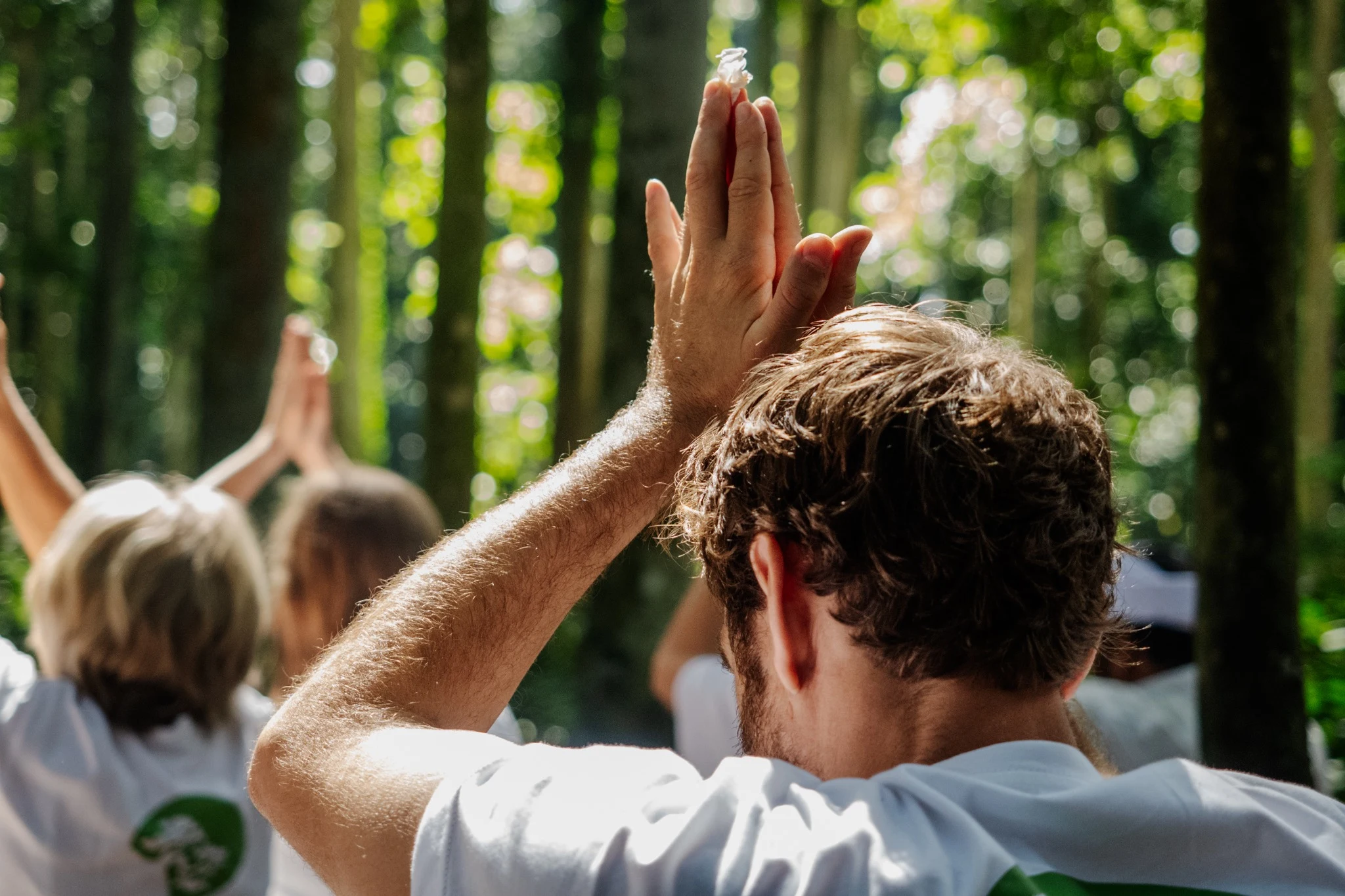 Max raising his hands during a group practice among tall trees