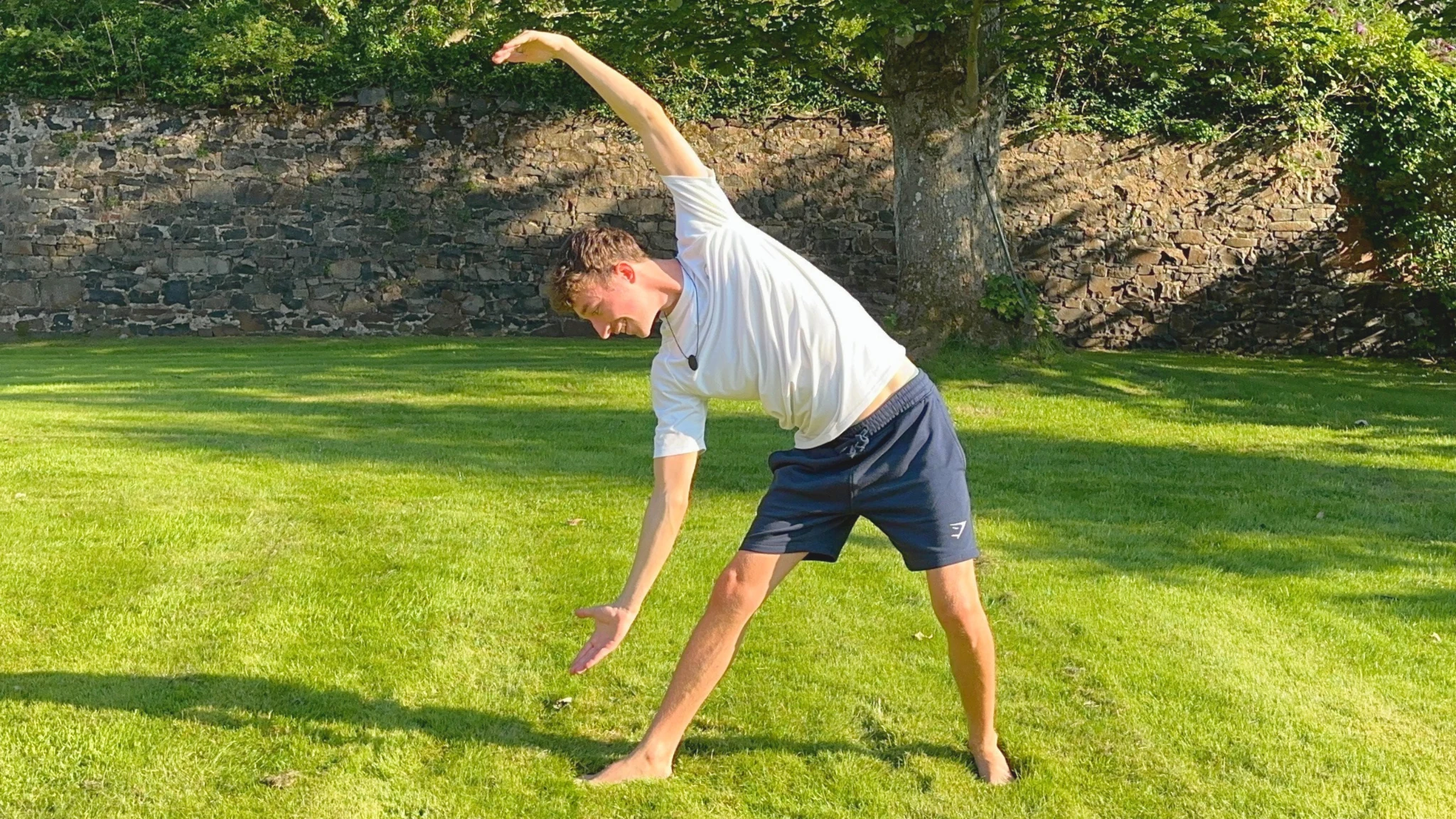Max practising a standing yoga posture in a sunny garden