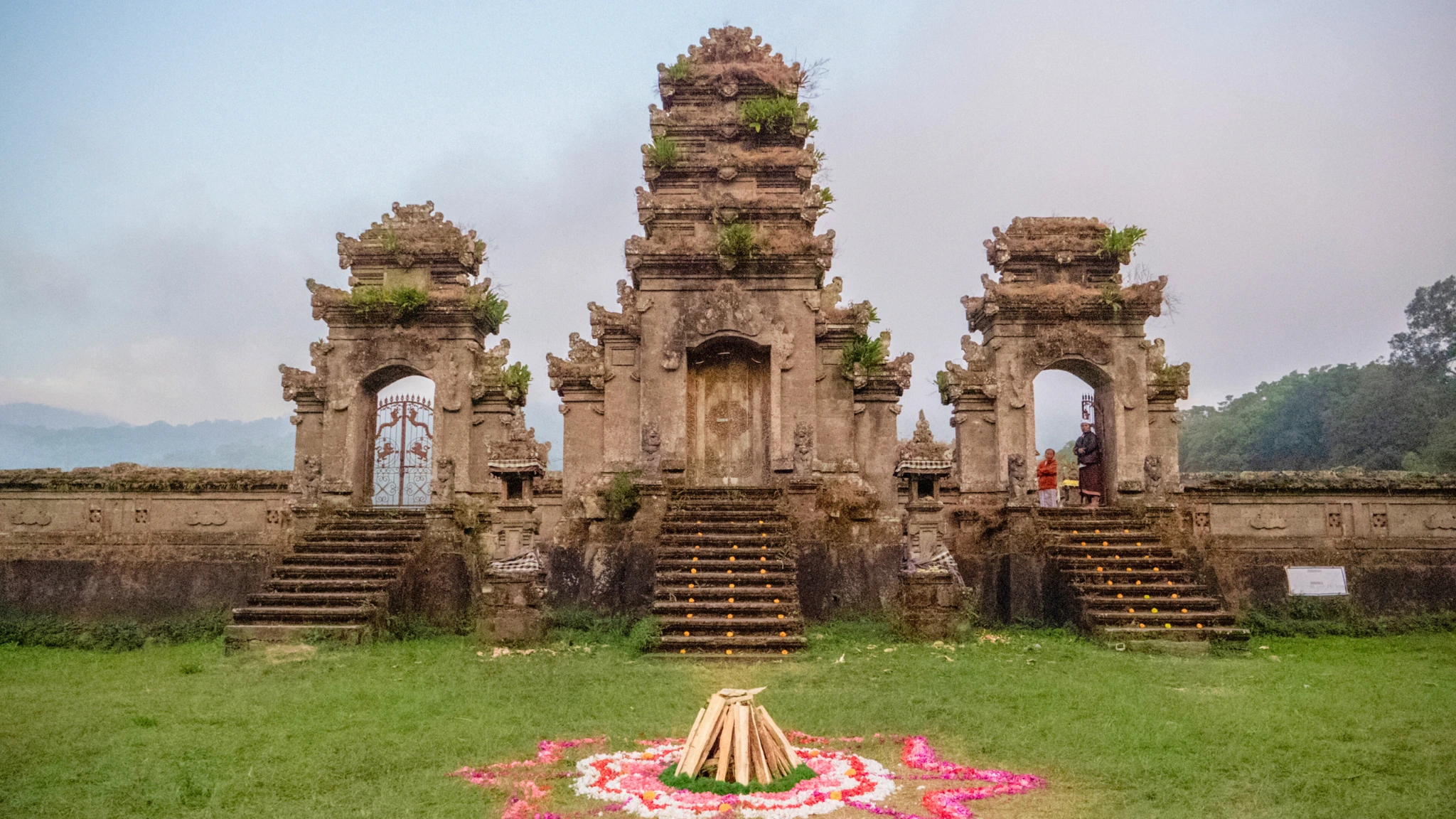 Balinese temple towers with a colourful flower offering in the foreground