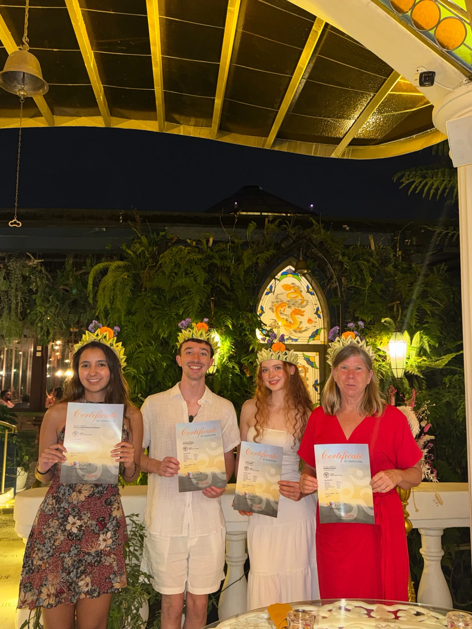 Max and fellow students holding certificates beneath a pavilion at night